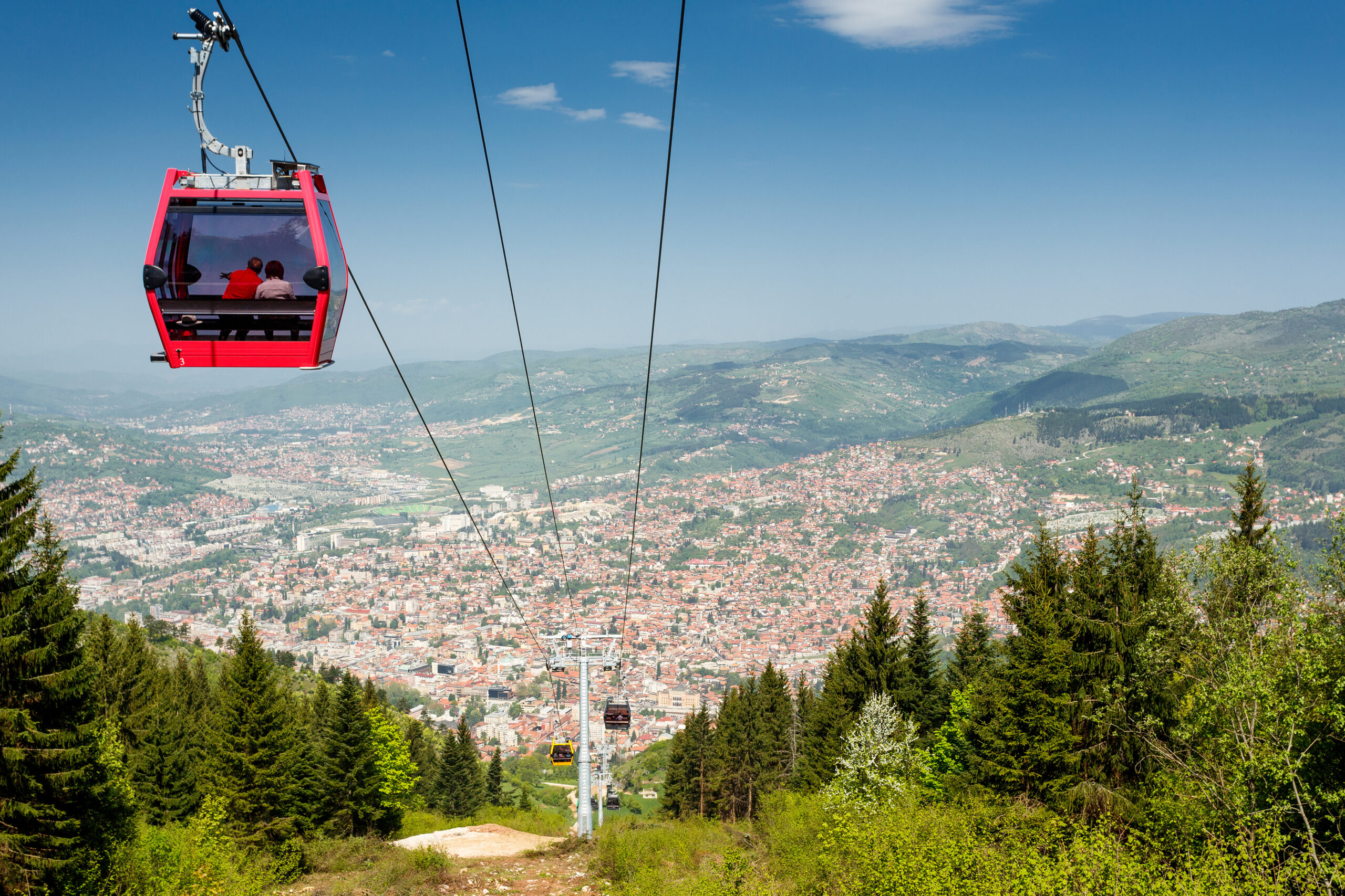 red-cable-car-facing-the-valley-with-rural-areas-and-town