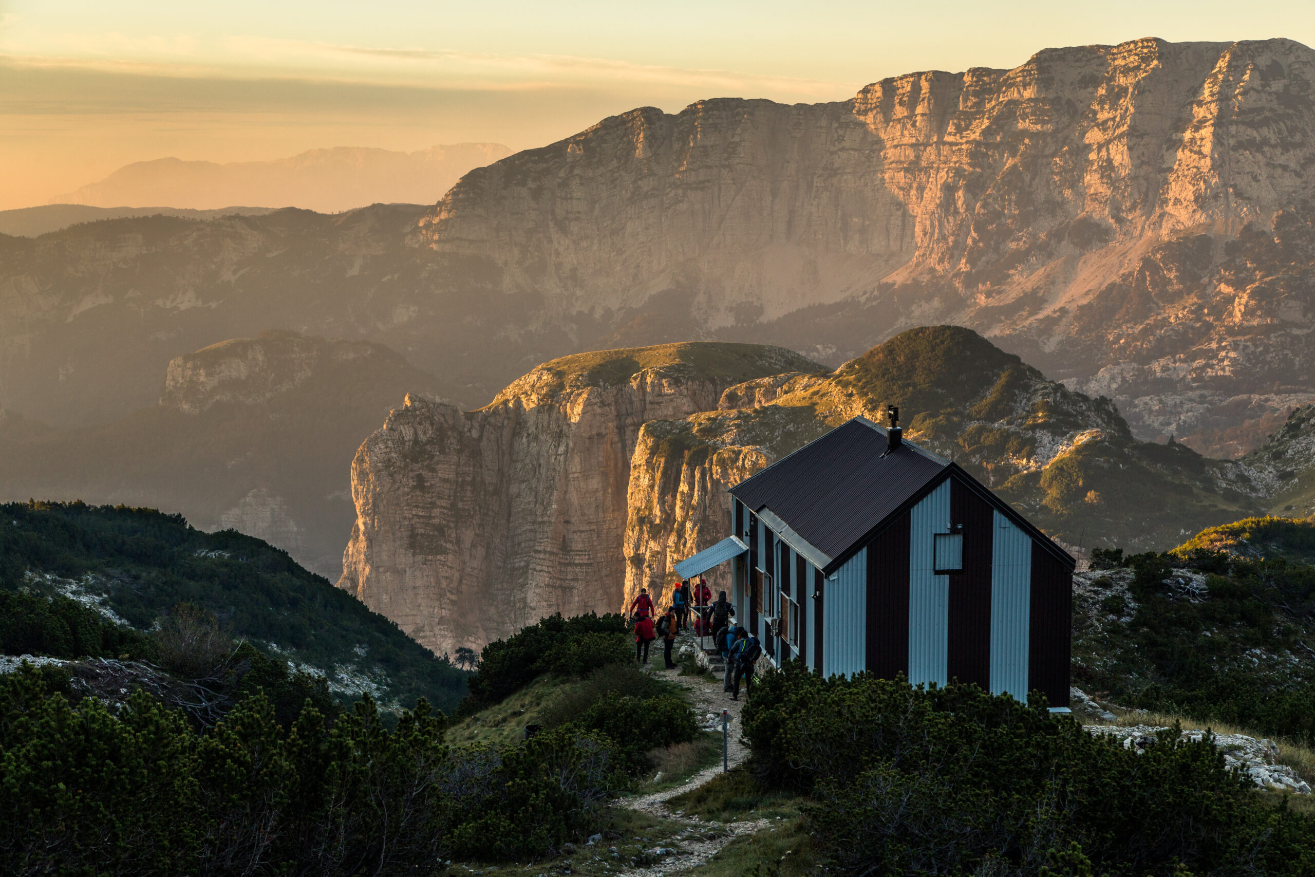 mountain-hut-at-sunset-with-hikers